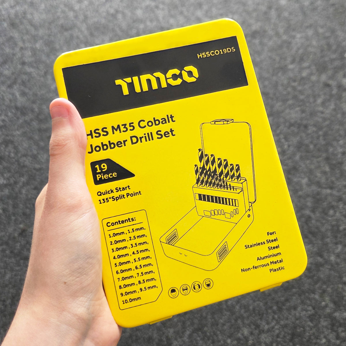 Hand holding a yellow Timco drill bit set packaging against a gray background