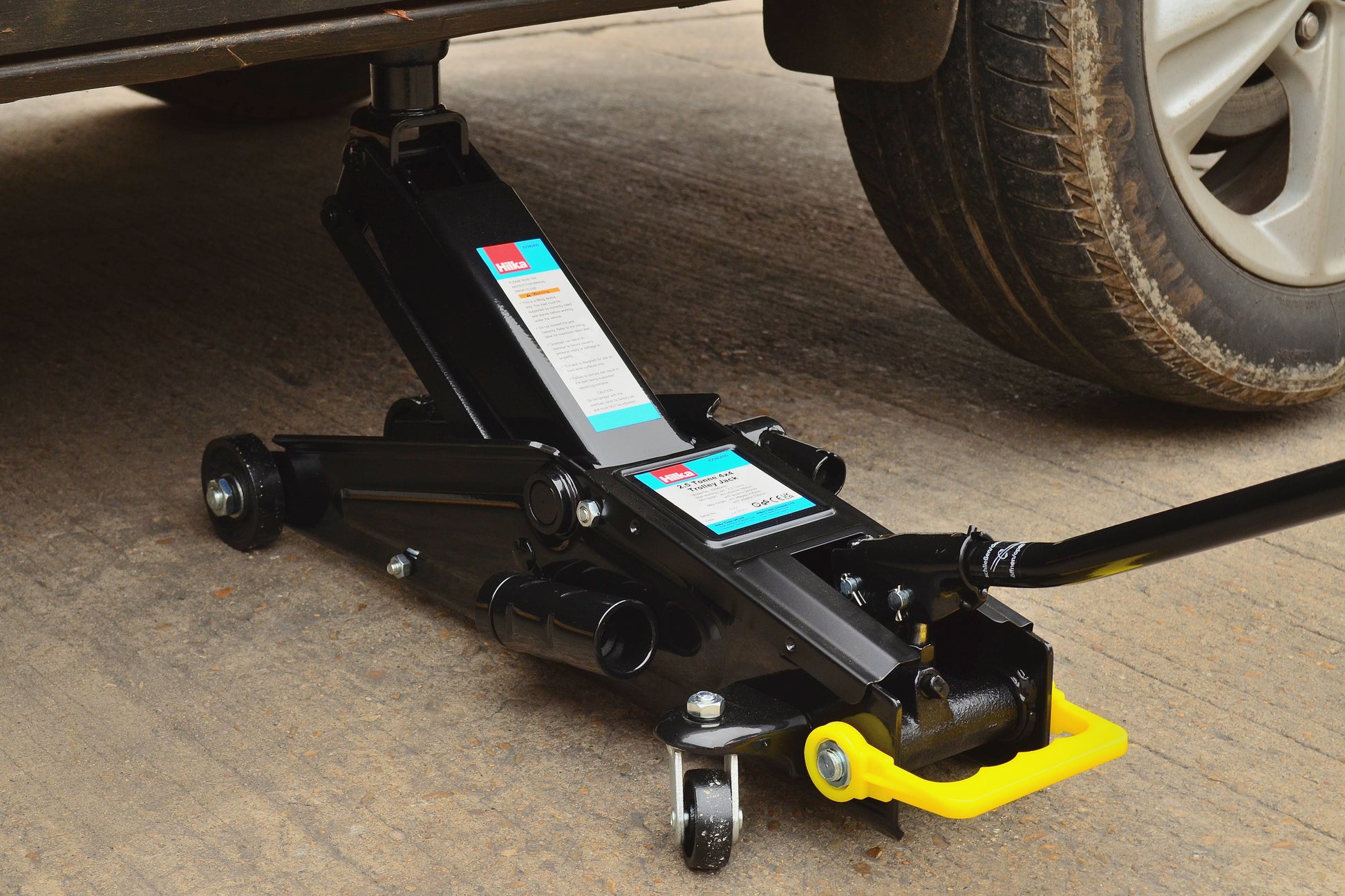 Tow bar jack under a vehicle on a concrete surface