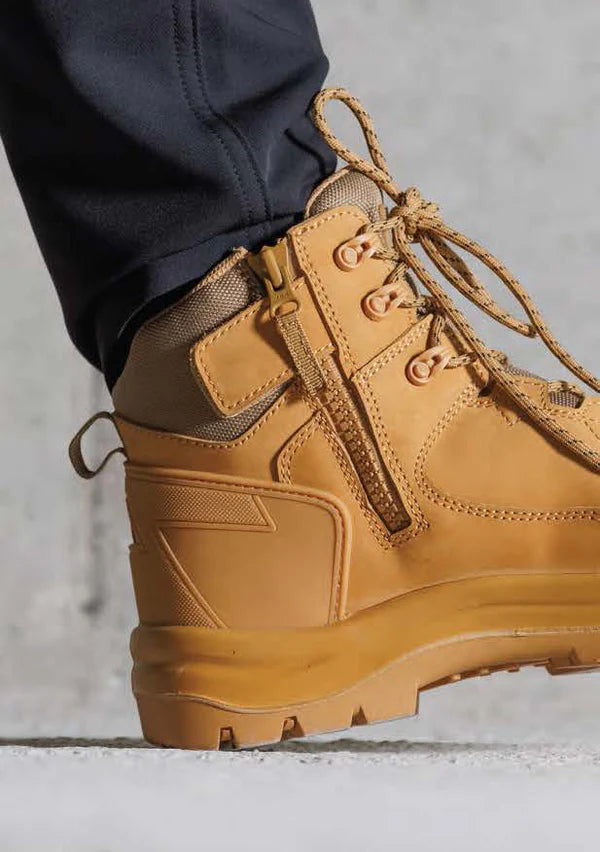 Tan hiking boot with laces on a neutral background