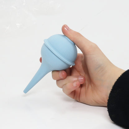 Hand holding a blue silicone bulb syringe against a white background