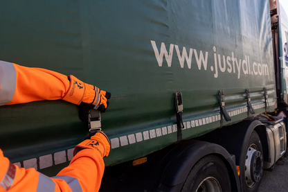 Person in orange safety gear securing a green trailer