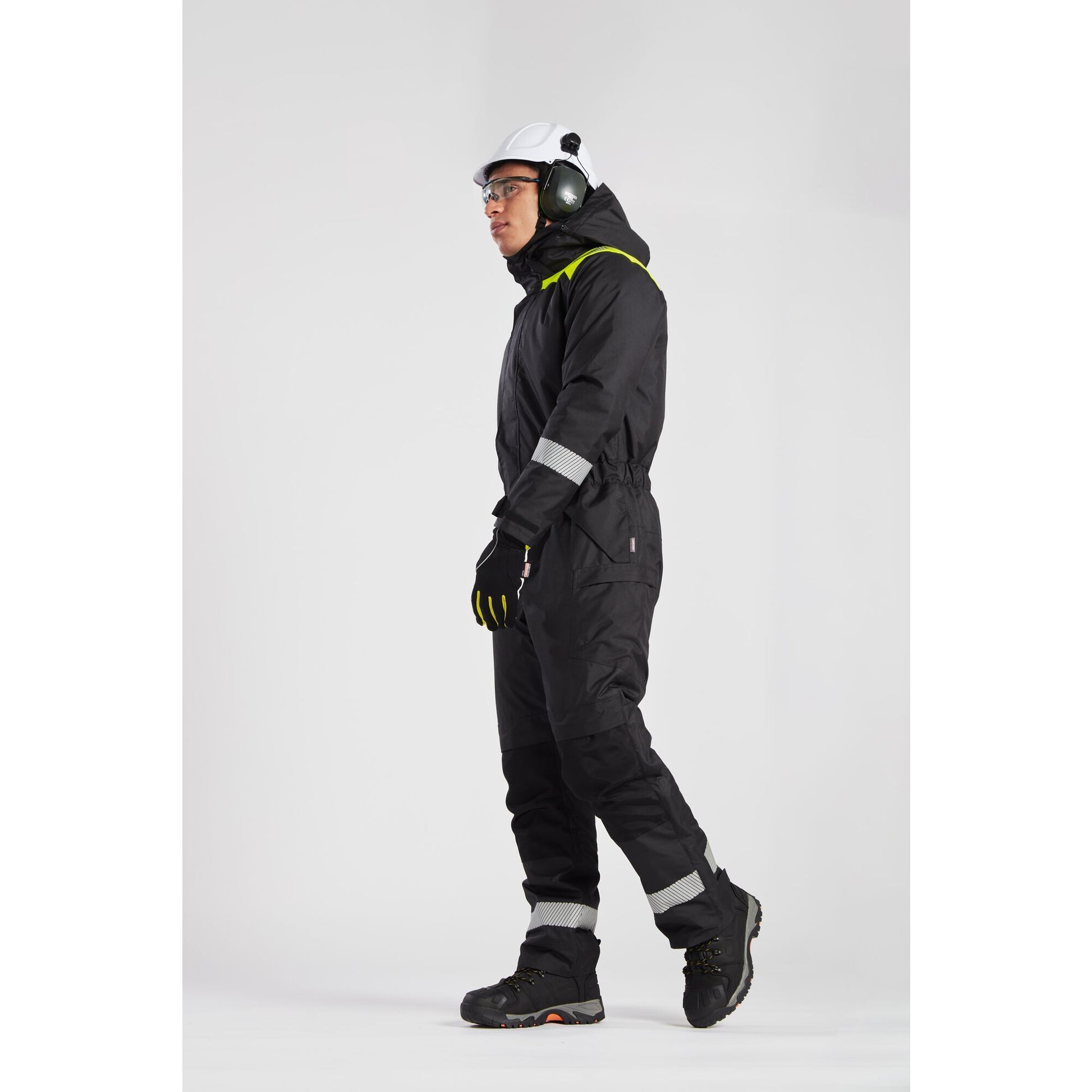 Person wearing a black snowsuit with reflective elements on a white background